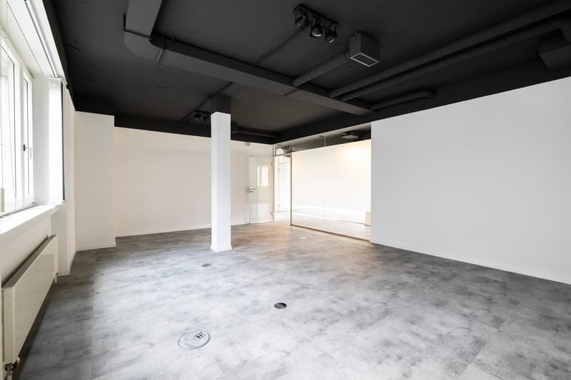 large open space, concrete floors, glass walls, exposed beams