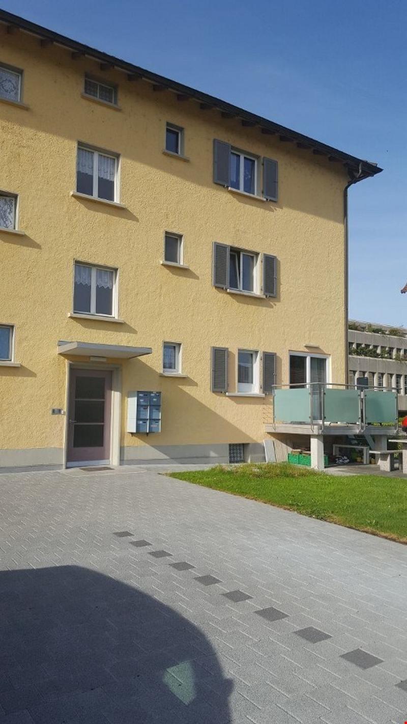 3 story building, yellow exterior, multiple windows, parking area, entrance