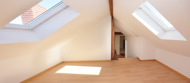 empty attic room with wooden floor, two skylights, wooden beam