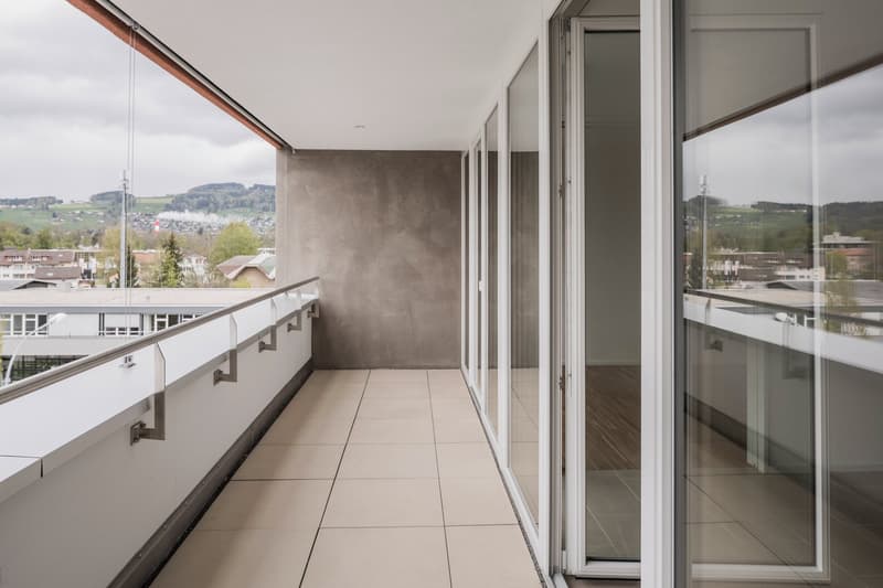 large balcony, sliding glass doors, tiled floor, metal railing, view of the city