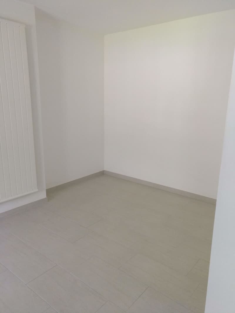 Empty room with white walls and gray tile flooring. The room appears to be a blank canvas, ready for furnishing and decorating.