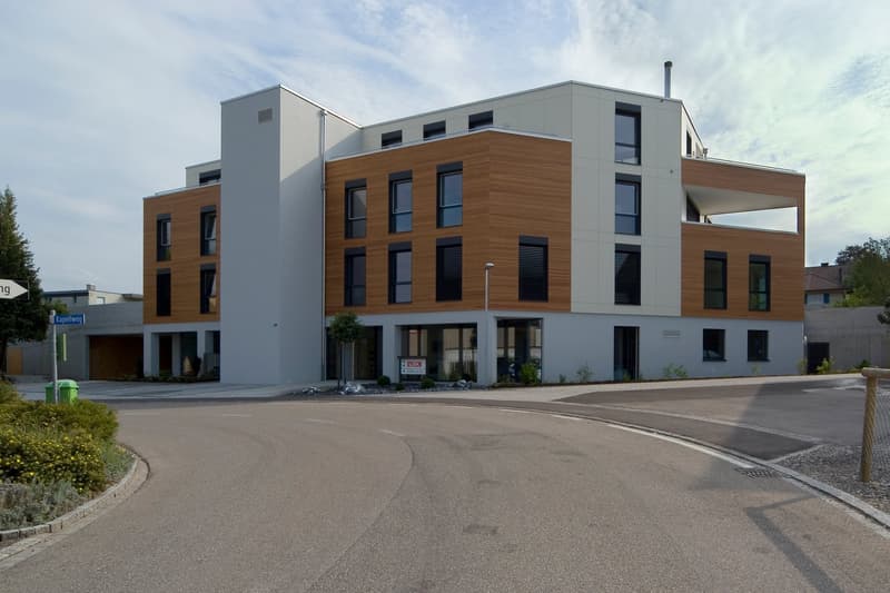 3 story modern apartment building, white and brown facade, many windows