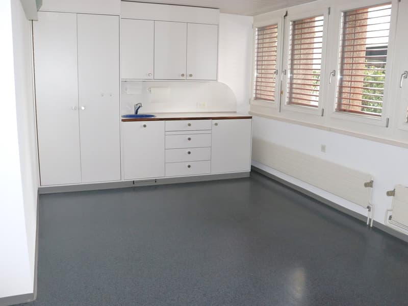 Empty room with kitchen, cupboards, sink, faucet, and windows with blinds.