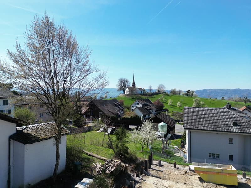 Houses in a village, green hills, church, clear blue sky, construction site