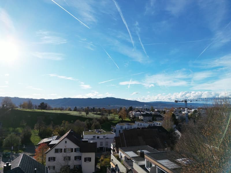 Aerial view of a town with houses, mountains, and a clear blue sky