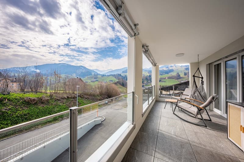 large balcony, glass railing, modern furniture, panoramic view of mountains
