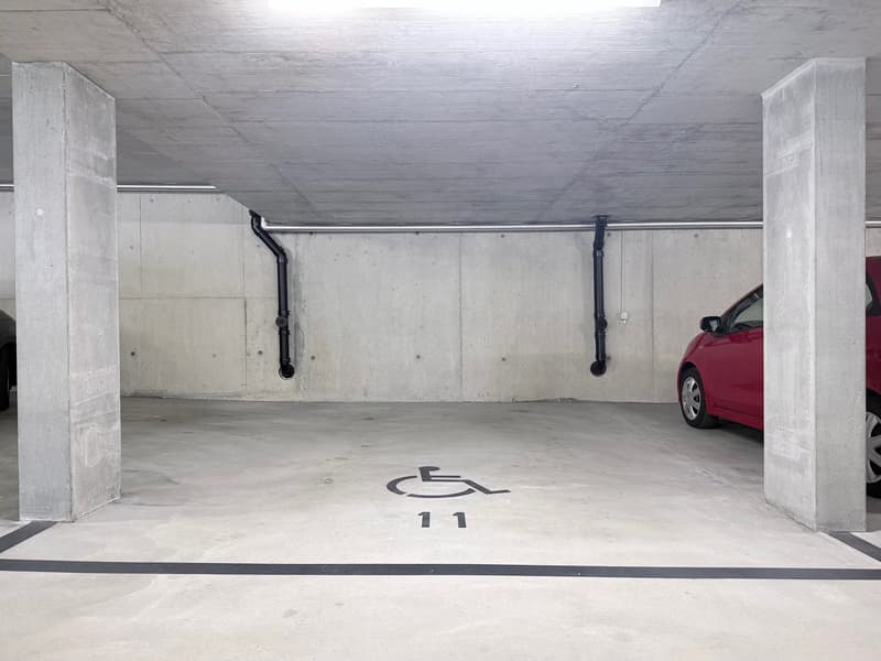 underground parking garage, concrete walls, white floor, designated parking spot number 11