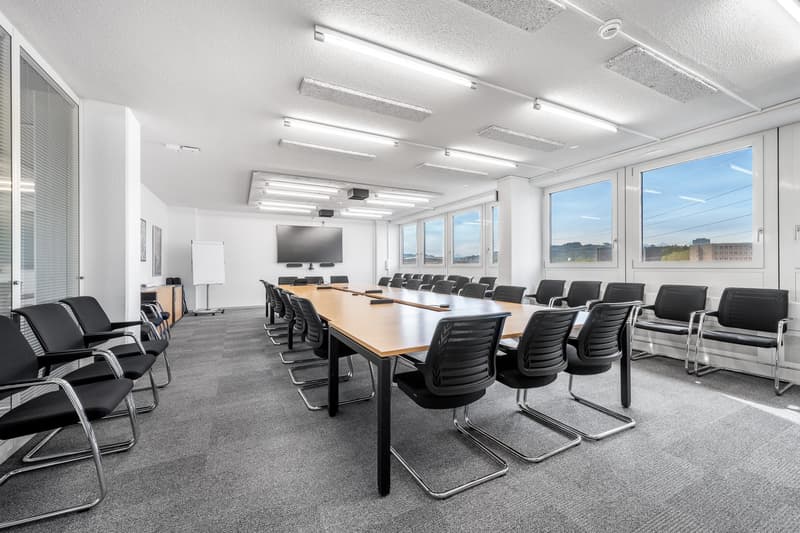 modern style, carpeted floor, large windows, long wooden desk, modern conference chairs, mounted TV, whiteboard, ceiling lights