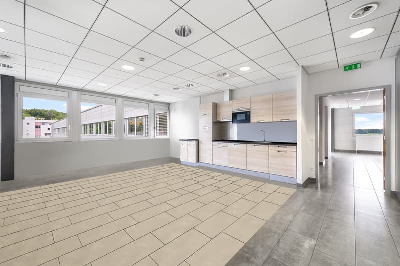 Open kitchen area with light tiled flooring, wooden cabinets, large windows, ceiling lights