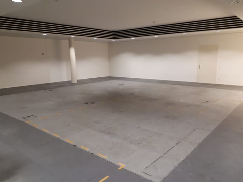 Empty parking lot, white walls, gray floor, white ceiling, yellow line markings, pillar