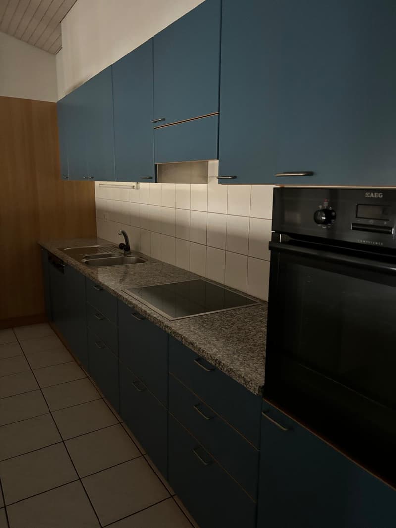 Modern kitchen with dark blue cabinets, white tile backsplash, granite countertops, and a built-in dishwasher