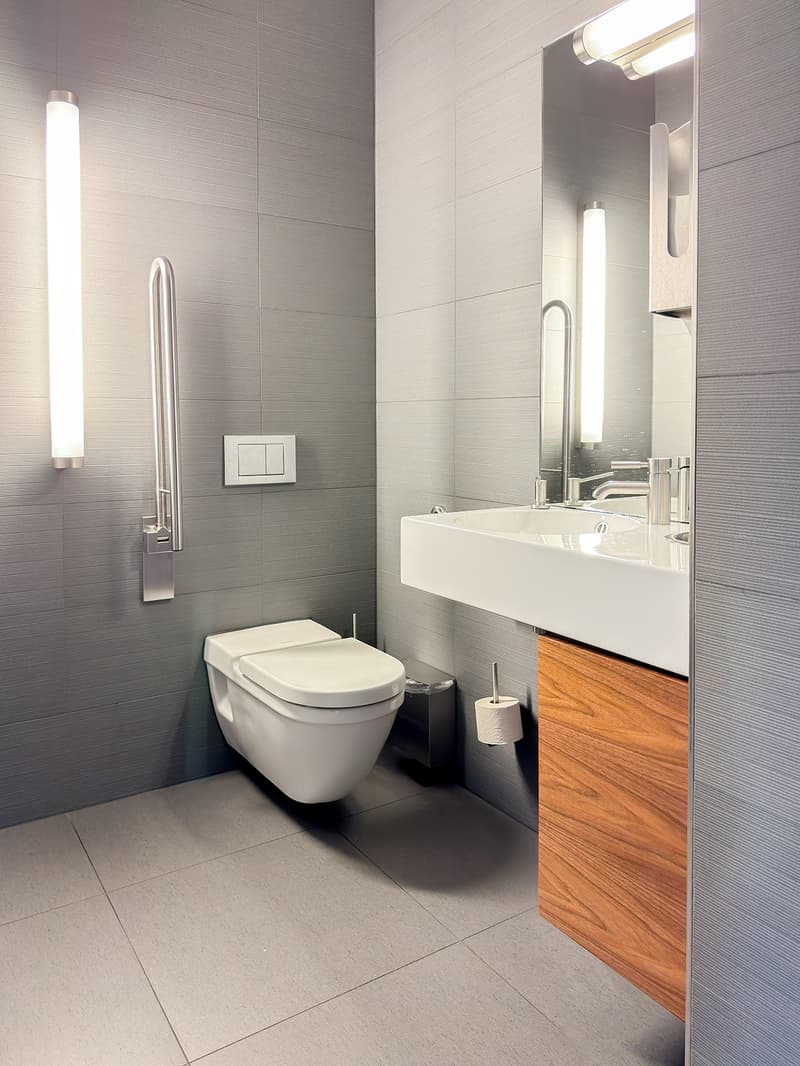 white tile walls, white tile floor, white toilet, sink, modern design, mirror, faucet
