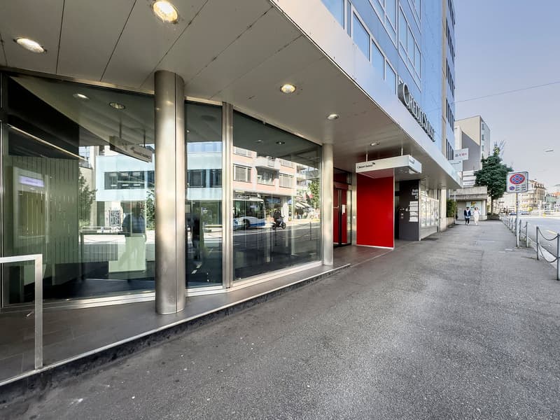 glass entrance, metal pillars, red door, large glass windows, sidewalk, street