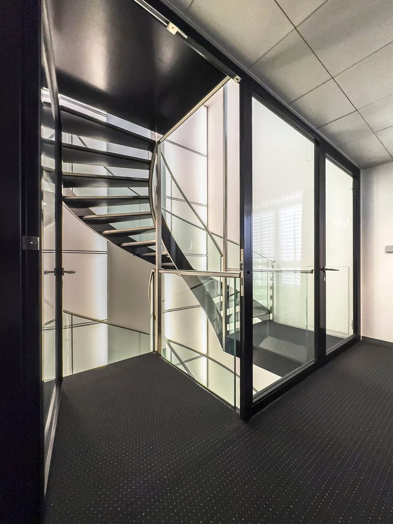 Sleek glass staircase with metal handrail, glass doors, carpeted floor, and modern interior design.