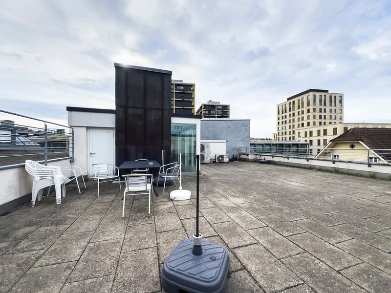 Roof terrace with tables, chairs, and a metal railing
