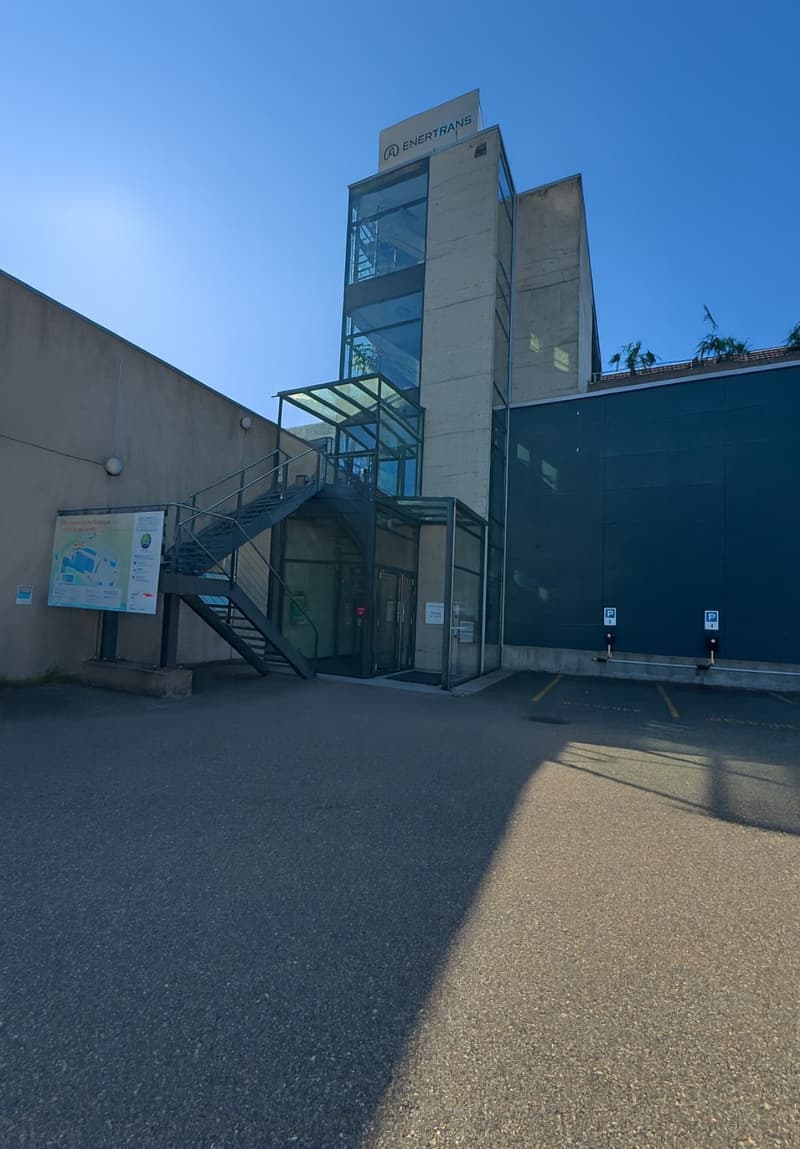 large multistory building with entrance, stairs, and parking area