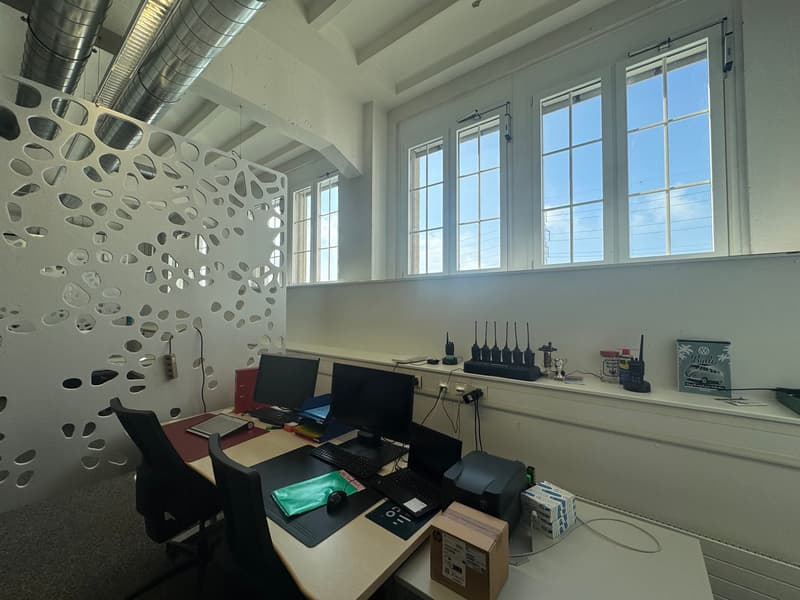modern office, computer desk with multiple monitors, keyboards, and boxes, large windows, white walls