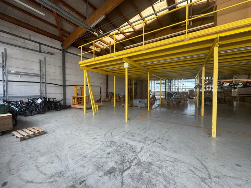 Warehouse with yellow steel framework, large open space, white floor, bicycles, pallet, boxes