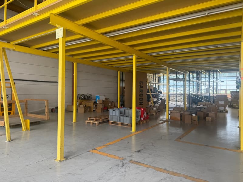 Warehouse interior, metal pillars, yellow frame structure, ground floor elevated, storage boxes, large windows