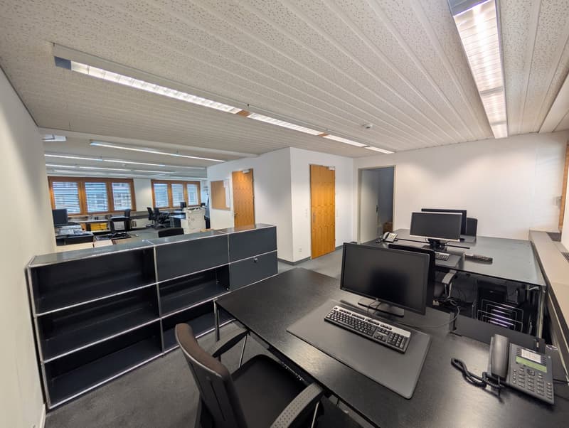 modern office space with desks, monitors, keyboards, telephones, shelves, and doors