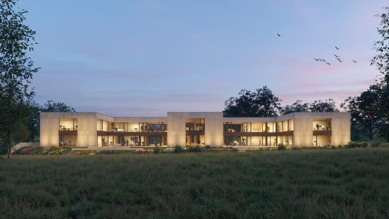 Large modern two-story house with glass walls and windows, surrounded by a grassy field and trees. The house has a sleek, minimalist design with a warm, inviting lighting visible through the windows at dusk.