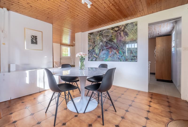 room with dining table, chairs, vase with flowers, wooden ceiling, white walls, floor tiles, picture frame