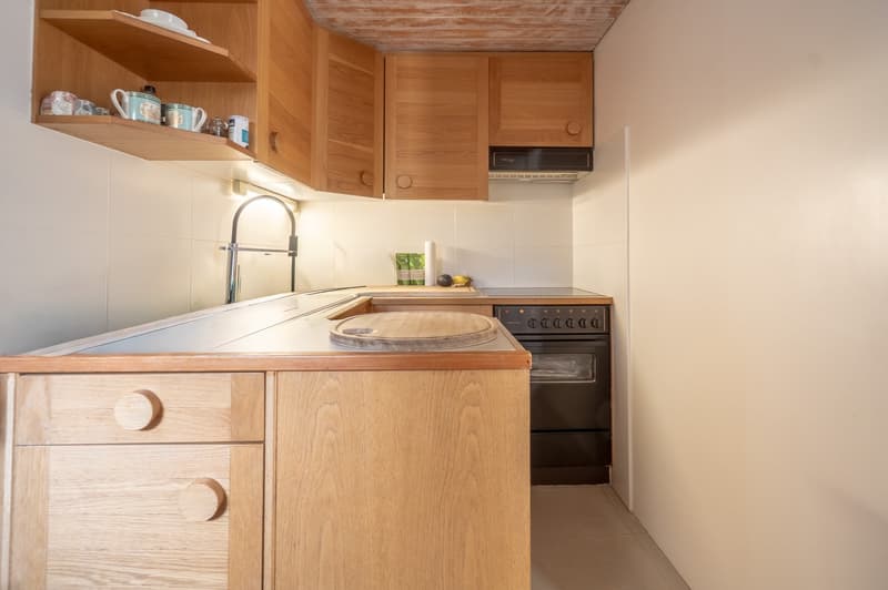 wooden cabinets, light tiled walls, light tiled floor, oven and microwave built-in, sink with faucet