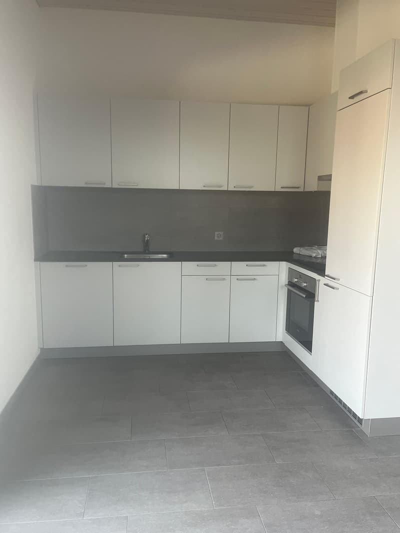 modern kitchen with white cabinets, black countertops, stainless steel sink, oven, dishwasher, washing machine