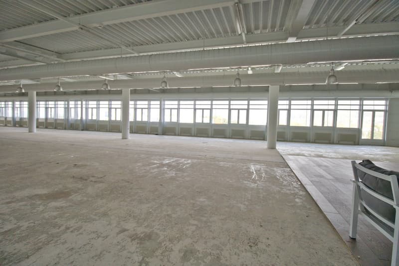 large open space, concrete floor, large windows, metal beams, white walls, hanging lamps