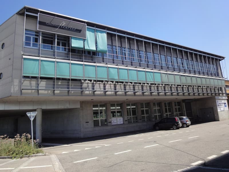 Modern office building with multiple floors, glass windows, metal balconies, and a sign that reads 'Galleries Floris' on the front.