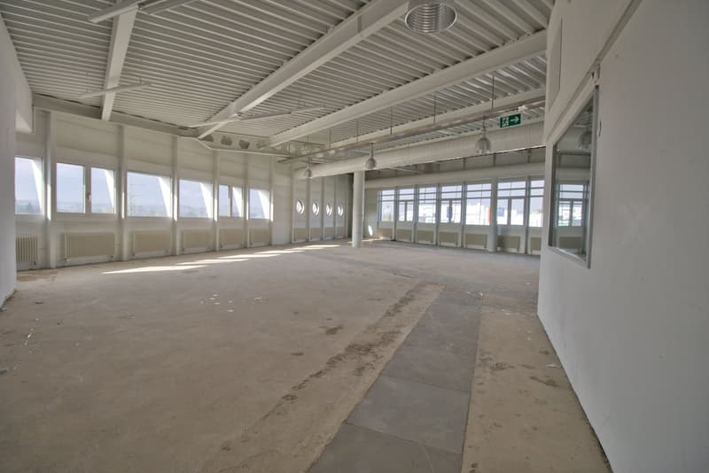 large open space, white walls, large windows, metal ceiling, metal beams, metal pipes