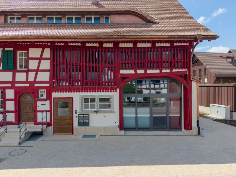2 story house, red and white facade, brown roof, wooden doors, glass doors, steps leading to entrance