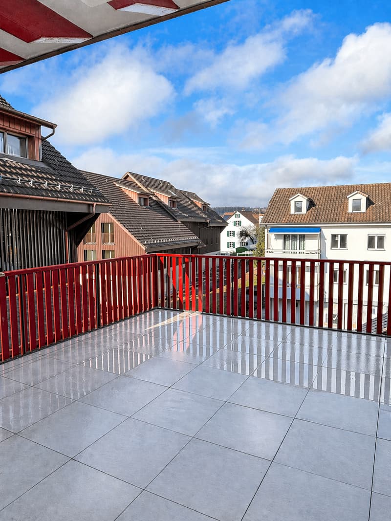 Balcony with red railing, tiled floor, view of the town