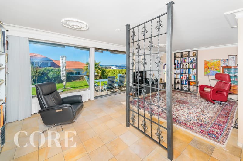 large windows, black leather chair, red chair, bookshelf, rug, metal gate, radiator