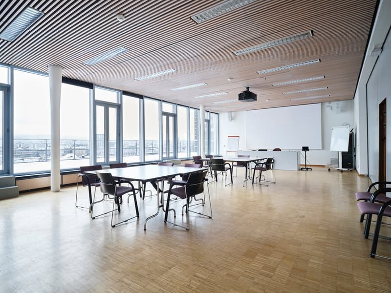 large windows, wooden floor, projector, tables, chairs, whiteboard, blank white wall