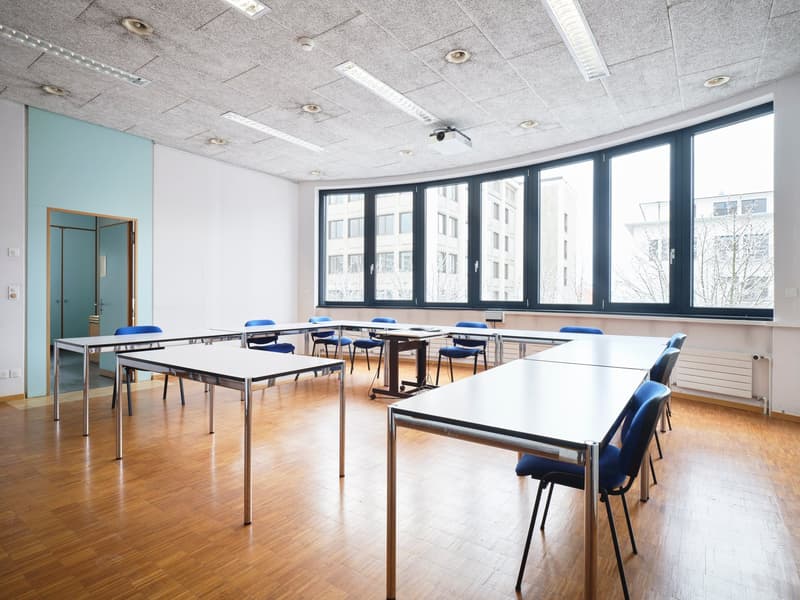white desk, blue chairs, projector, large windows