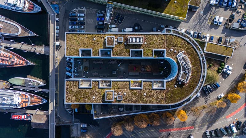 Commercial building with multiple levels, surrounding parking, rooftop garden, visible multiple windows