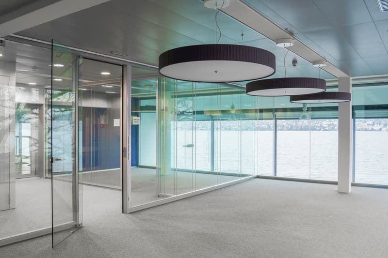 large glass wall with view, white ceiling, carpeted floor, round lamps