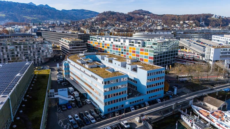 aerial view of several buildings and parking lots with multiple cars parked and green roofs