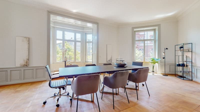 a long dining table with chairs, a bowl, white walls, wooden floors, windows