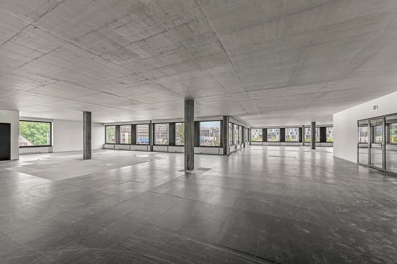 open room, large windows, gray tiled floor, concrete ceiling, doors at the end