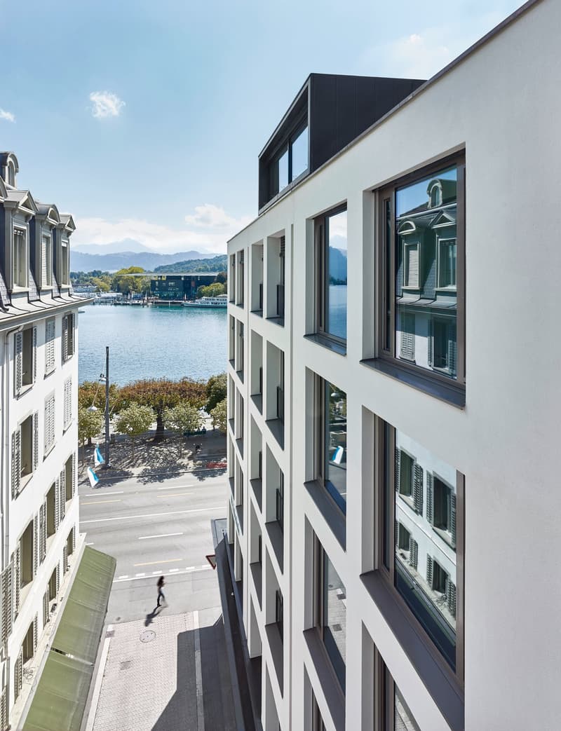 Exterior view of a modern building with glass windows and a lake view.