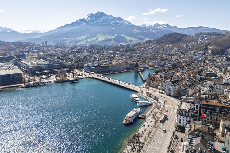 Aerial view of the city with mountains, a river, buildings, ships, and a bridge