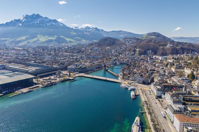 Aerial view of a city with a river, mountains, and buildings