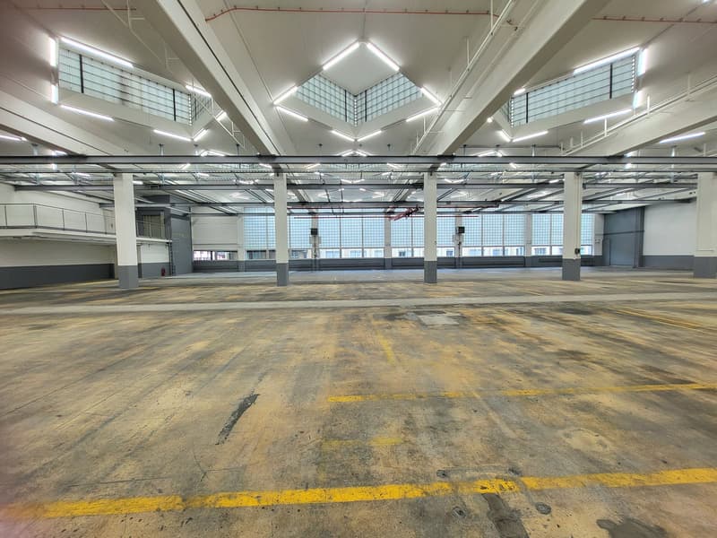 Industrial warehouse, concrete floor, high ceilings, multiple windows, no furniture, yellow markings