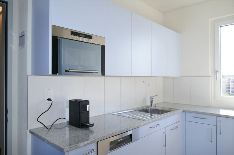 stainless steel microwave, dishwasher, granite countertop, stainless steel sink, faucet, power outlet, black coffee maker, white cabinets, white tiles