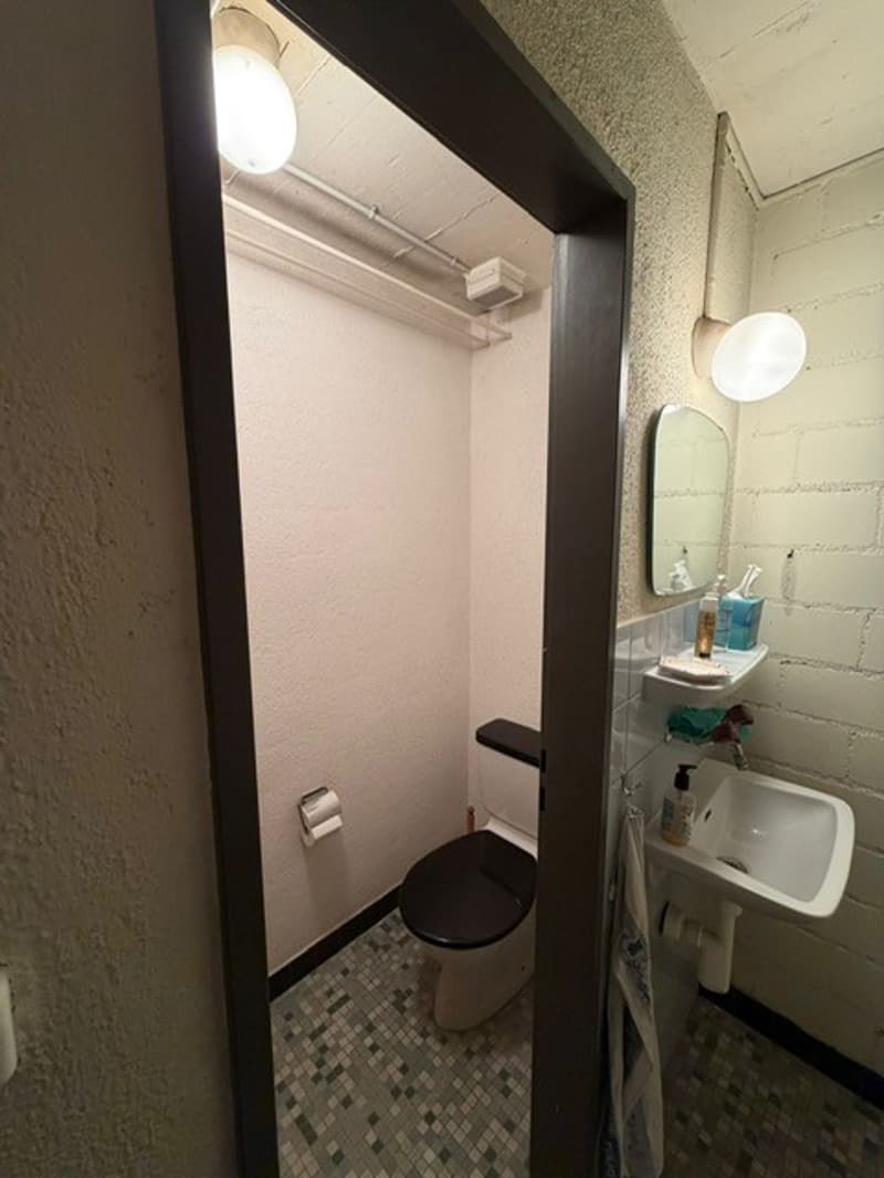 small bathroom with toilet, sink, mirror, and tiled floor