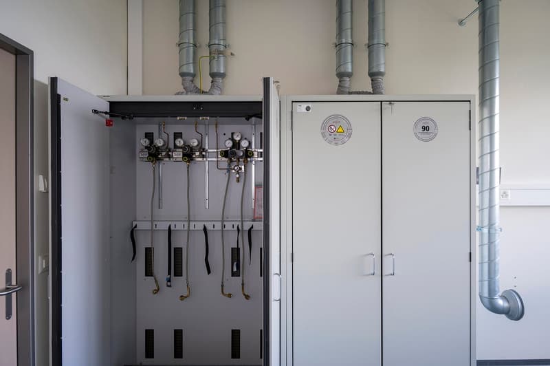 The image shows a utility room or mechanical room with various equipment and controls. There are multiple pipes, gauges, and control panels visible, indicating this is a room for managing the building's mechanical systems. The room appears to be well-orga