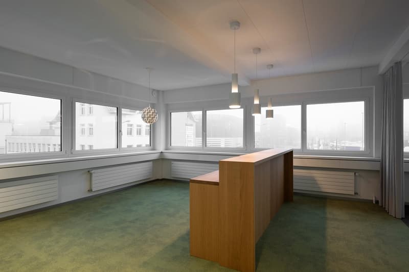 modern office with large windows, wooden desk, 4 hanging lamps, underfloor heating, green floor