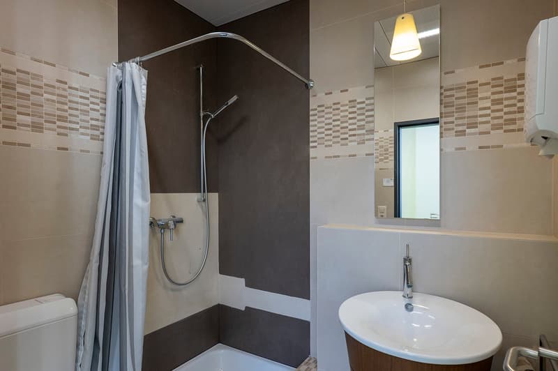white porcelain tiles, white shower, bathtub, sink, toilet, shower curtain, mirror, light fixture